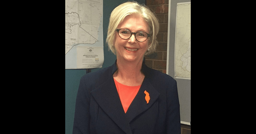 A blonde woman in glasses wearing an orange shirt