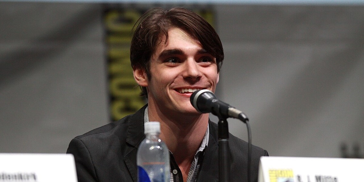 A brunette man sitting at a microphone