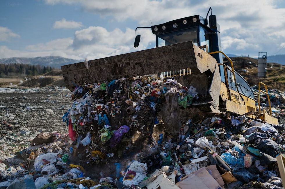 A bulldozer in a rubbish dump filled with garbage