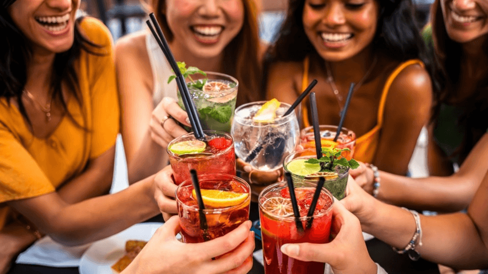 A bunch of women holding glasses of colourful liquid