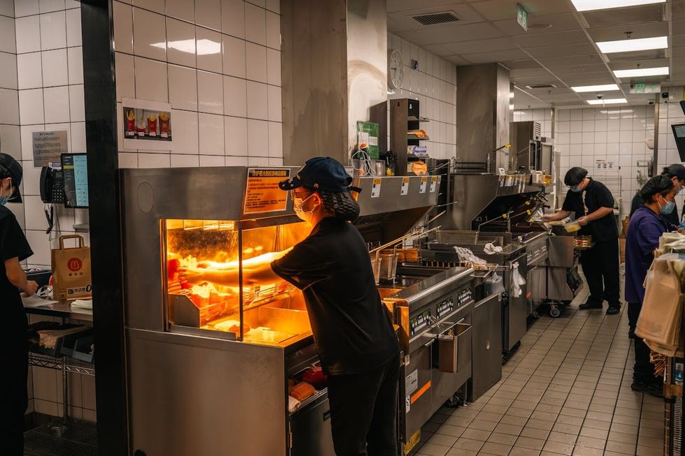 A busy restaurant kitchen including a worker standing over a hot stove