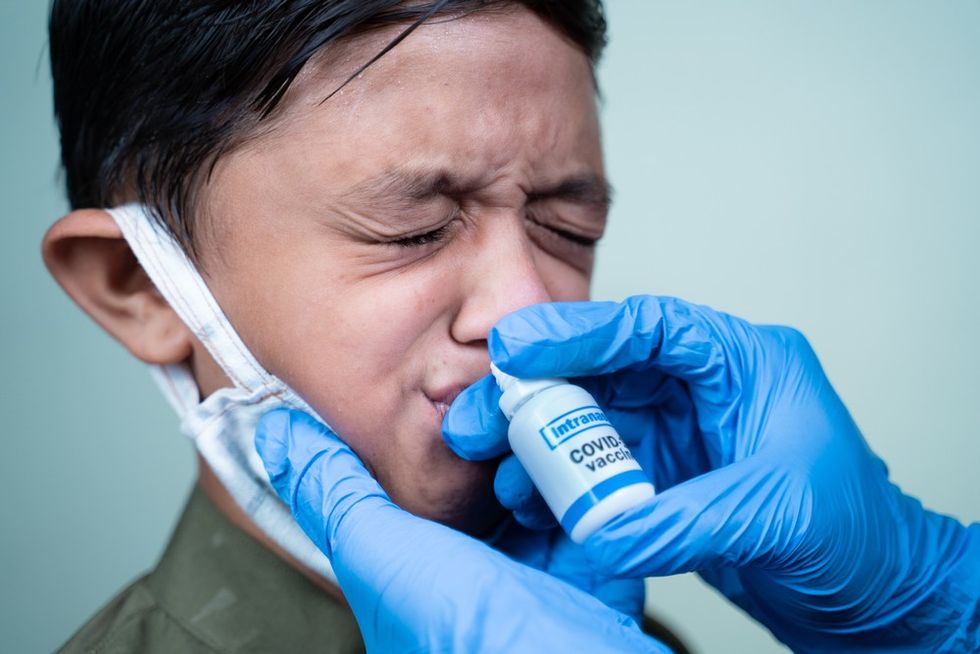 A child having a vaccine applied via a nostril