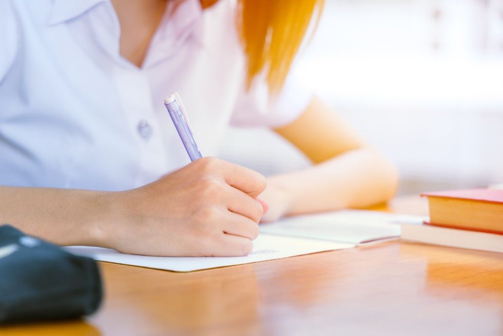 A close up of a student writing on a piece of paper