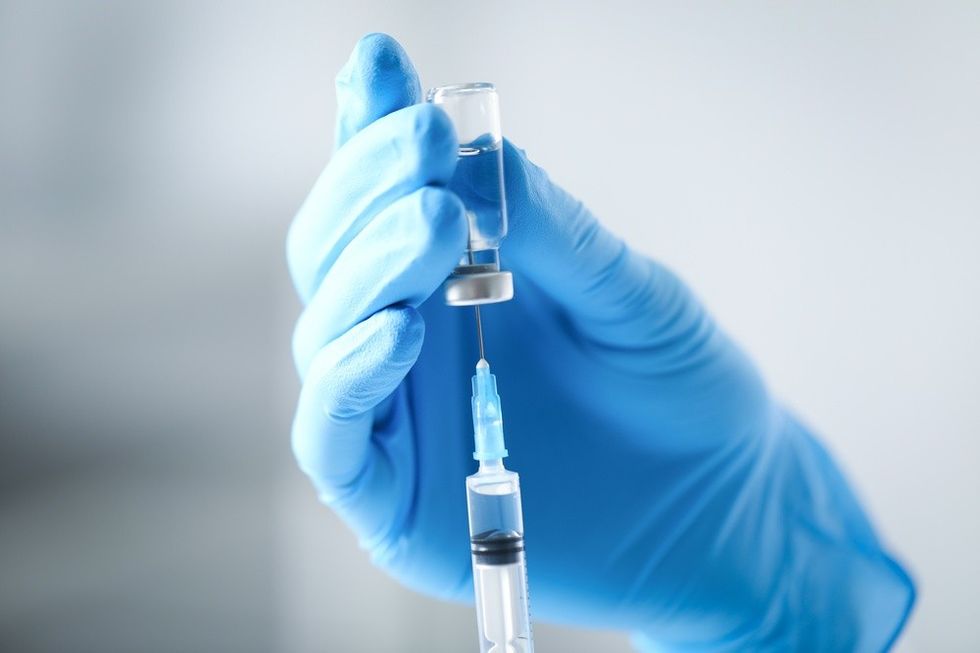 A close up of a vaccine held by a blue gloved hand