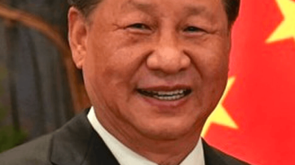 A close up of Xi Jinping's face against a Chinese flag