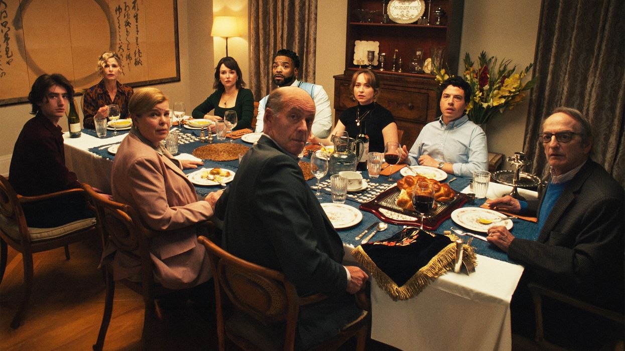 A family of nine looking up from the dinner table towards the camera.
