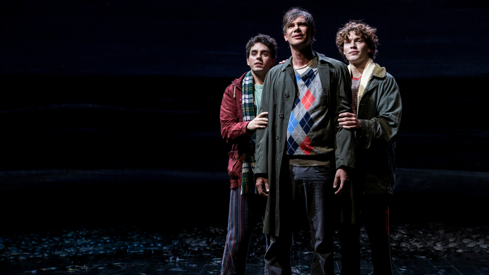 A father and two young men on stage look towards the sky