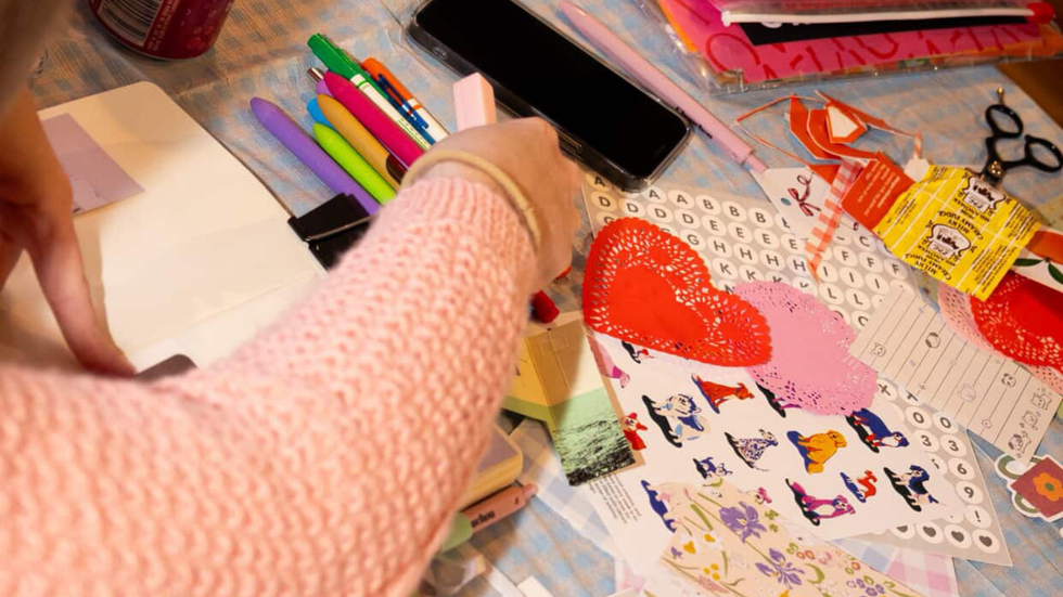 A girl junk journaling with crafting scraps and colourful pens.