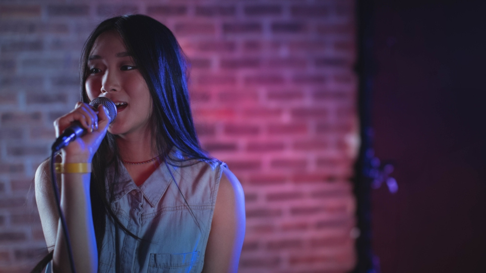 A girl sings into a microphone.