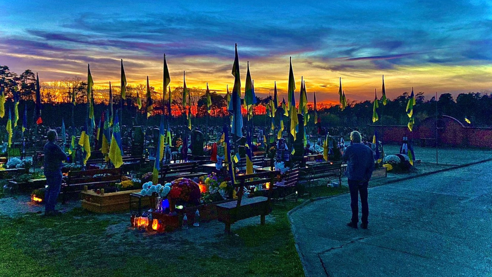 A graveyard with countless Ukrainian flags at sunset