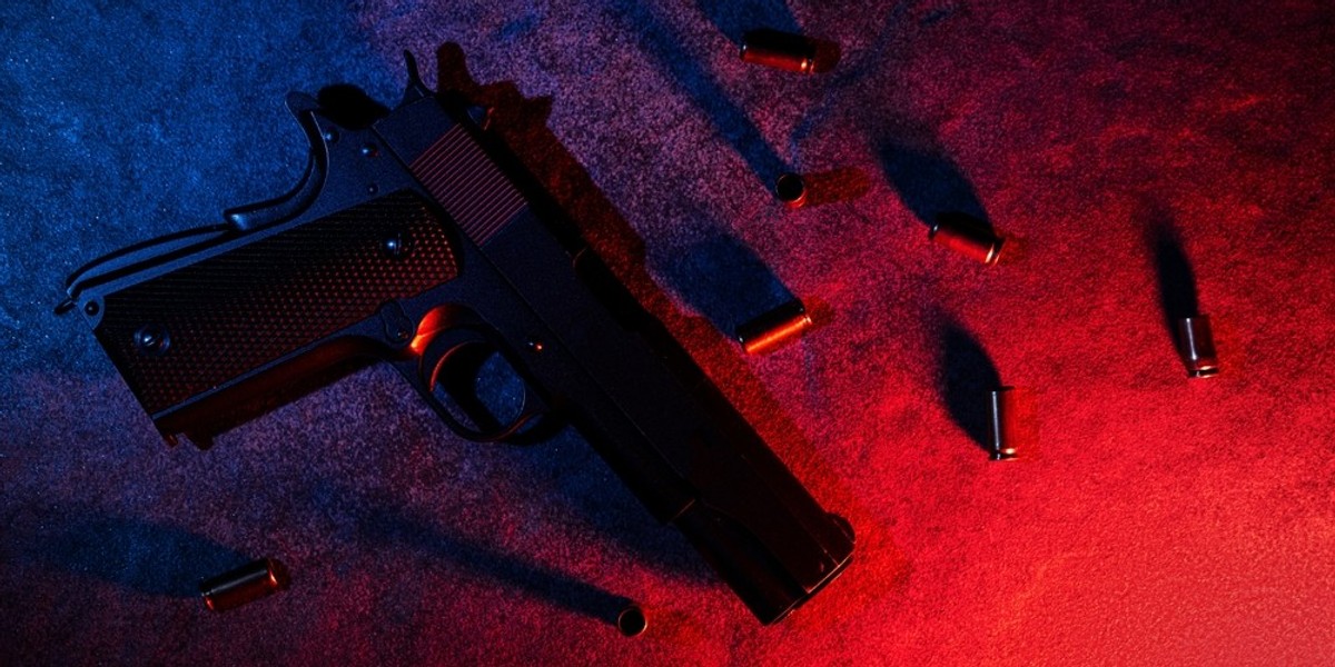 A gun laying on the ground amongst bullets