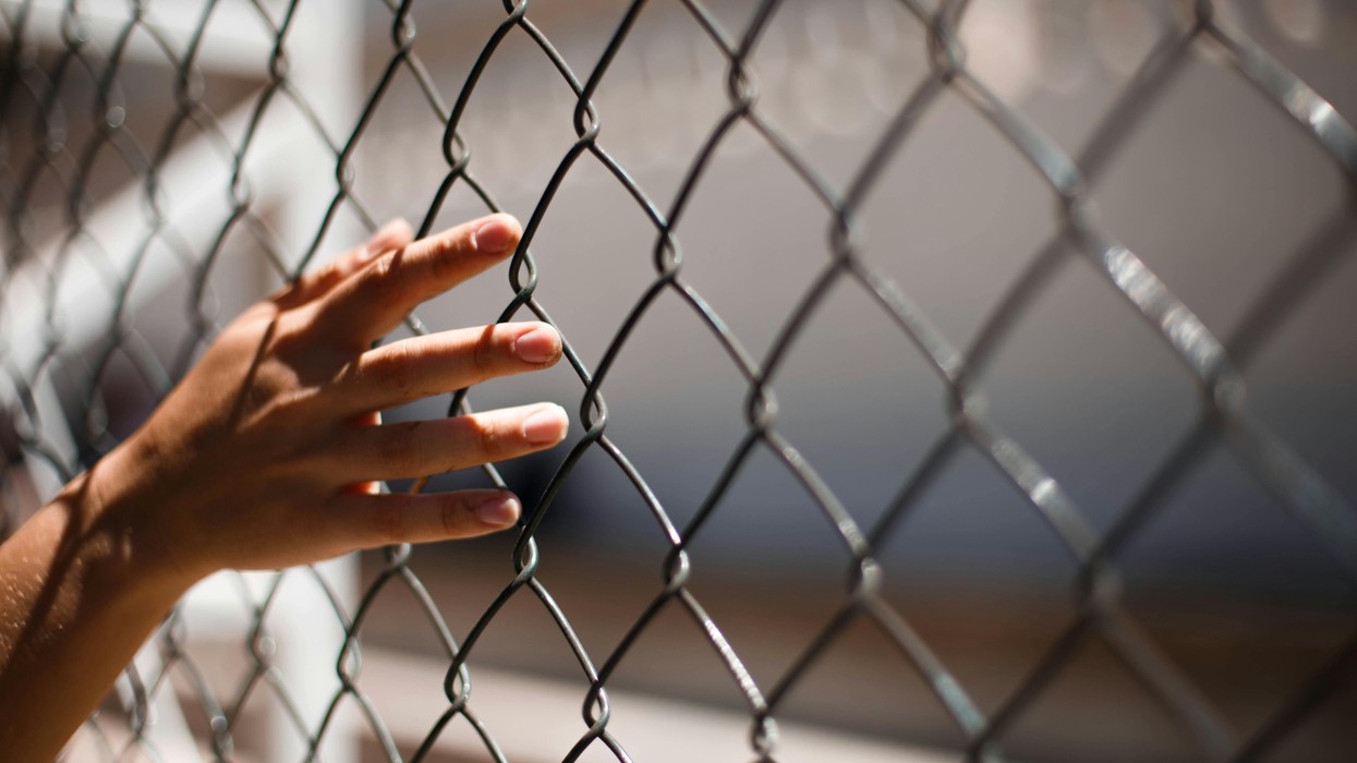 A hand against a fence