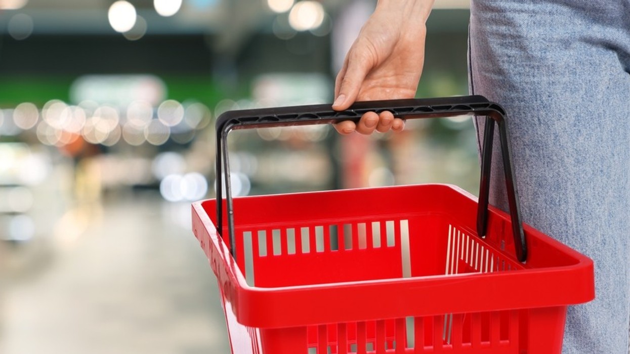 A hand holding an empty shopping basket