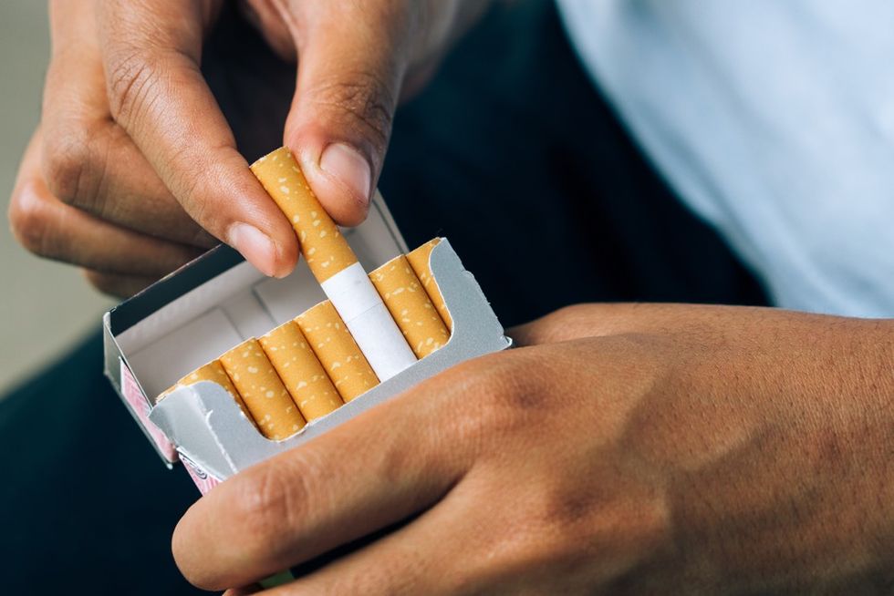 A hand takes a cigarette out of a packet