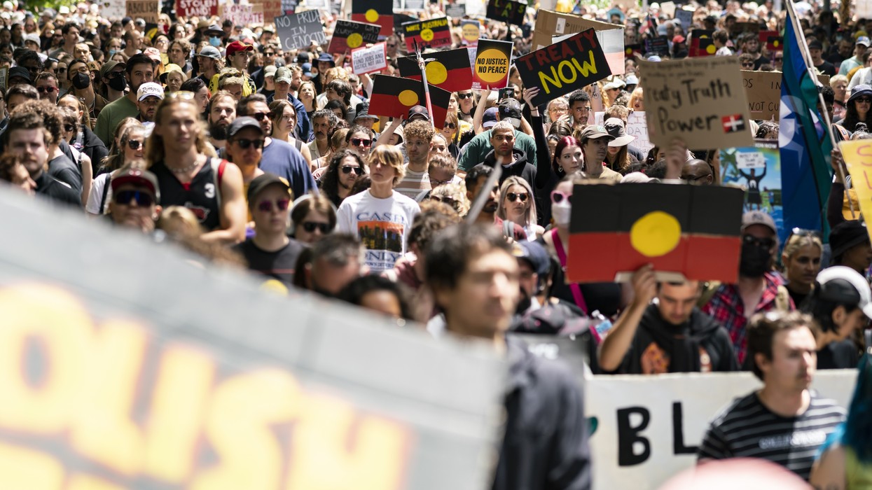 A large scale march with Indigenous flags flying