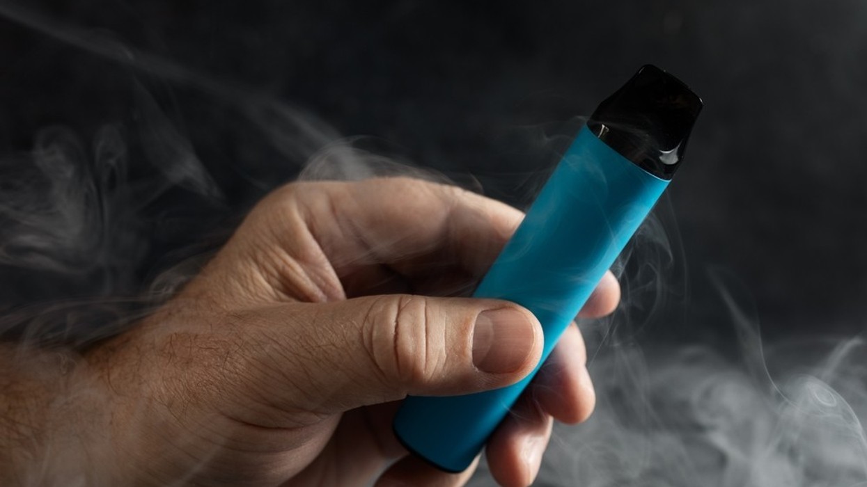A male hand holding a vape