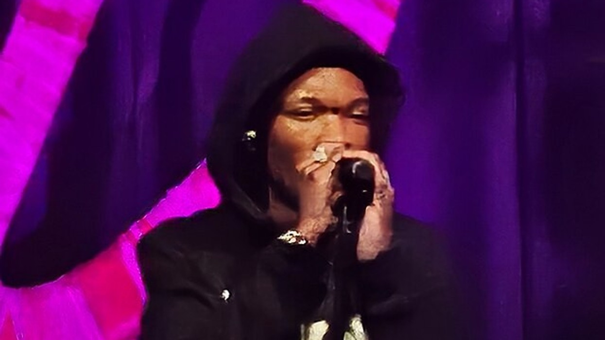 A man in a hoodie sings into the microphone