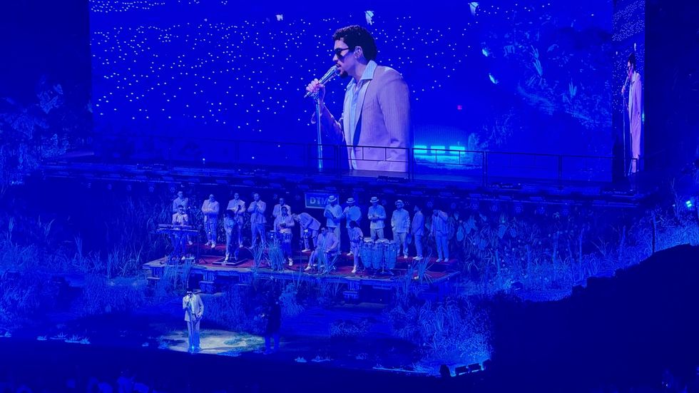 A man in a suit on a stage sings to the crowd