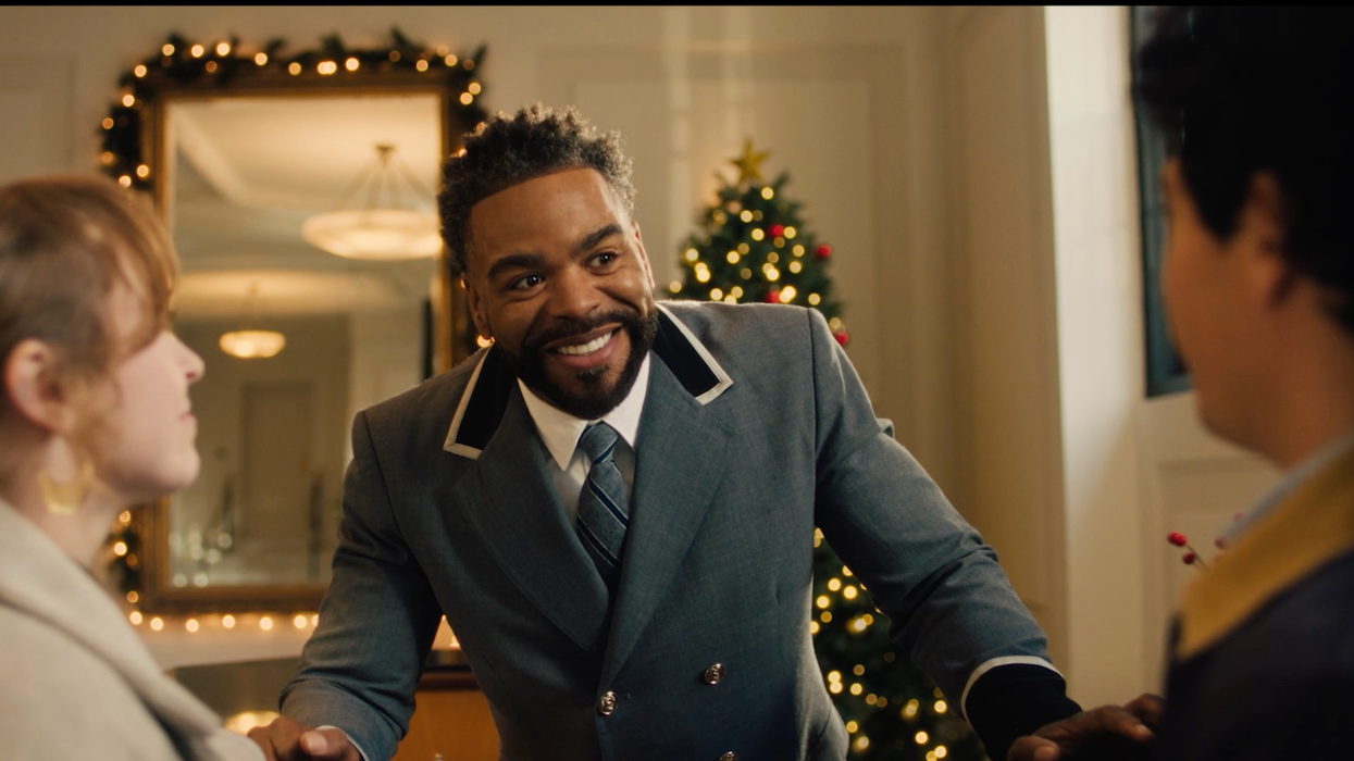 A man in a suit smiles at two young people