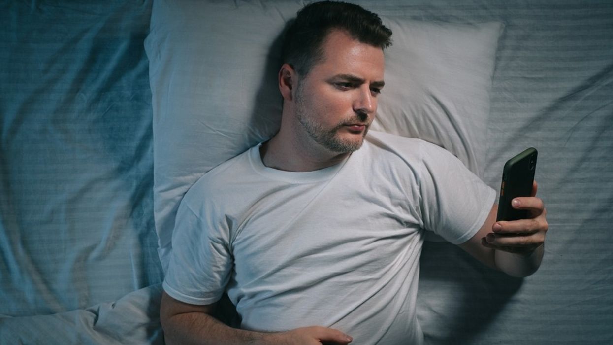 A man lying in bed looking at his phone
