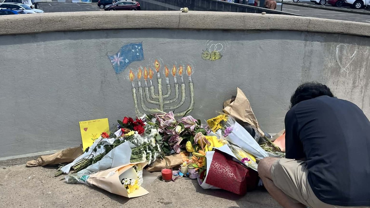 A man on the bridge at Bondi in front of a makeshift memorial for those killed and injured