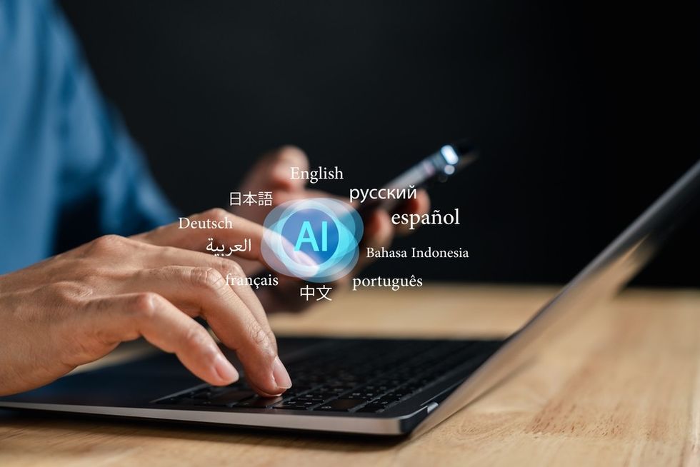 A man's hand hovers over a laptop keypad with graphics of language names above it.
