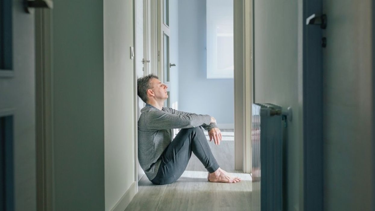 A man sits on the floor at the end of a long hallway