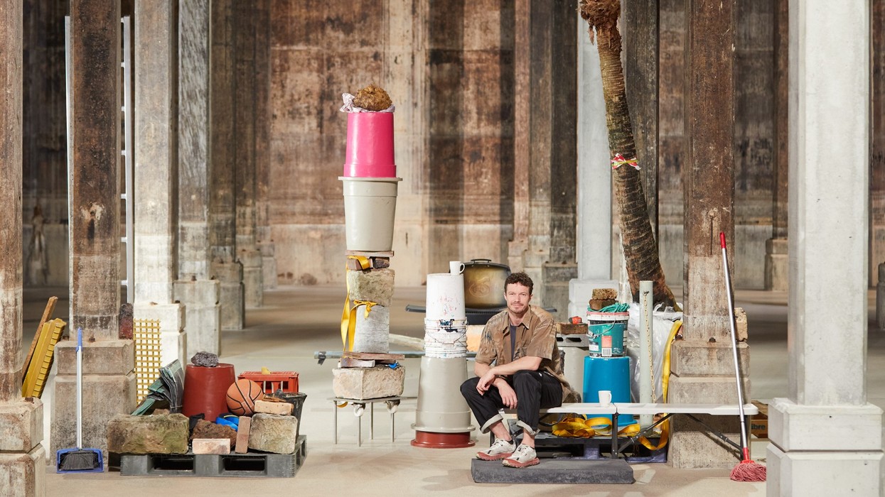 A man surrounded by props in a vast concrete room
