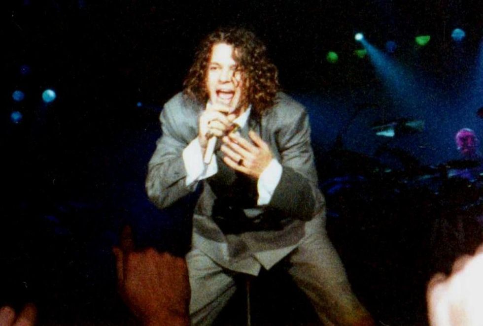 A man with curly hair sings into a microphone