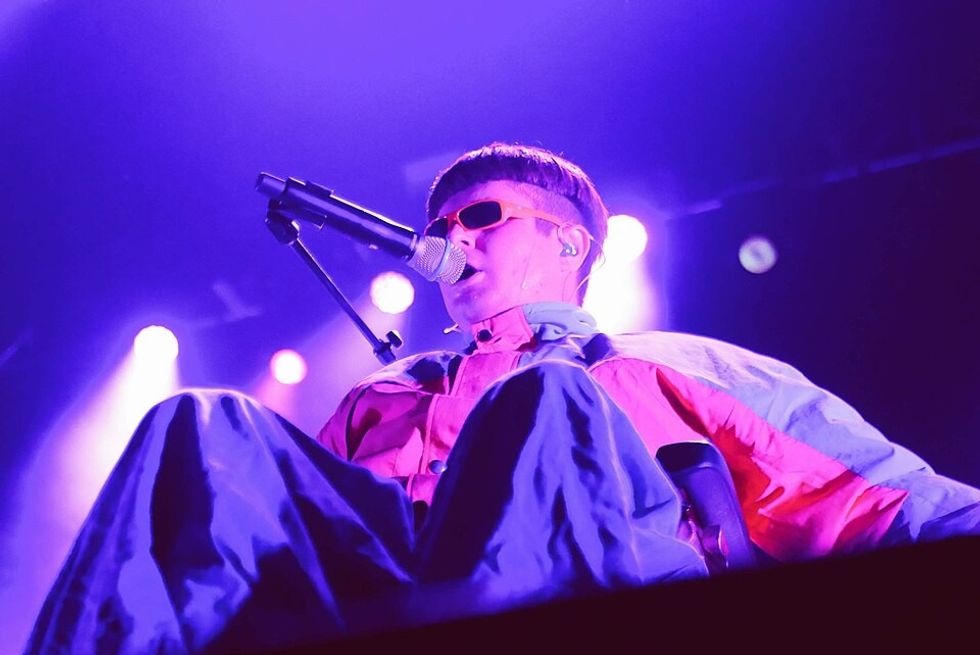 A man with dark hair sings into a microphone