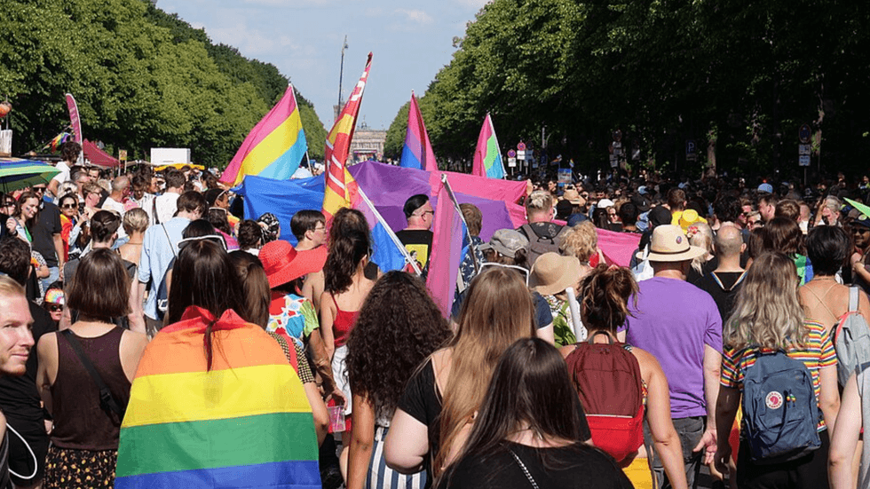 A march with participants holding rainbow flags