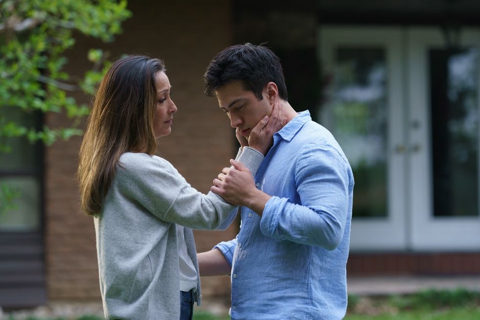 A mother puts her hand up to the face of a young man