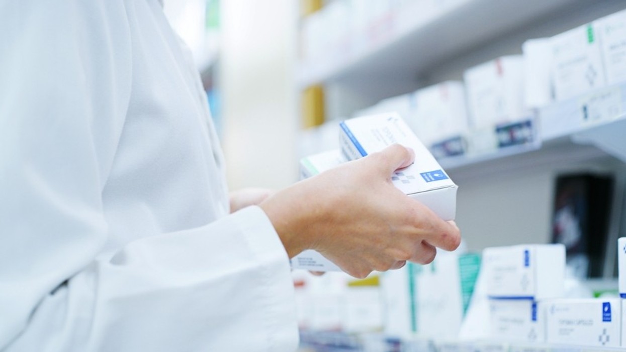 A person wearing a white coat looking at medication