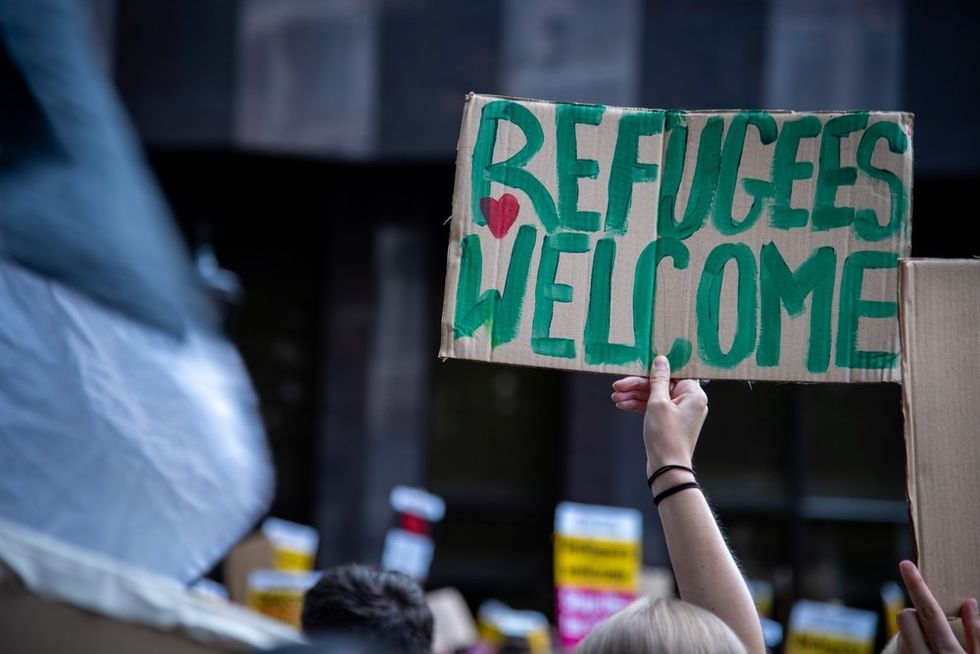 A protestor holds up a sign saying refugees welcome