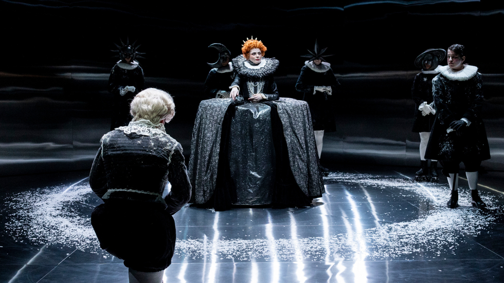 A queen character with bright orange hair stands in the centre of six figures.