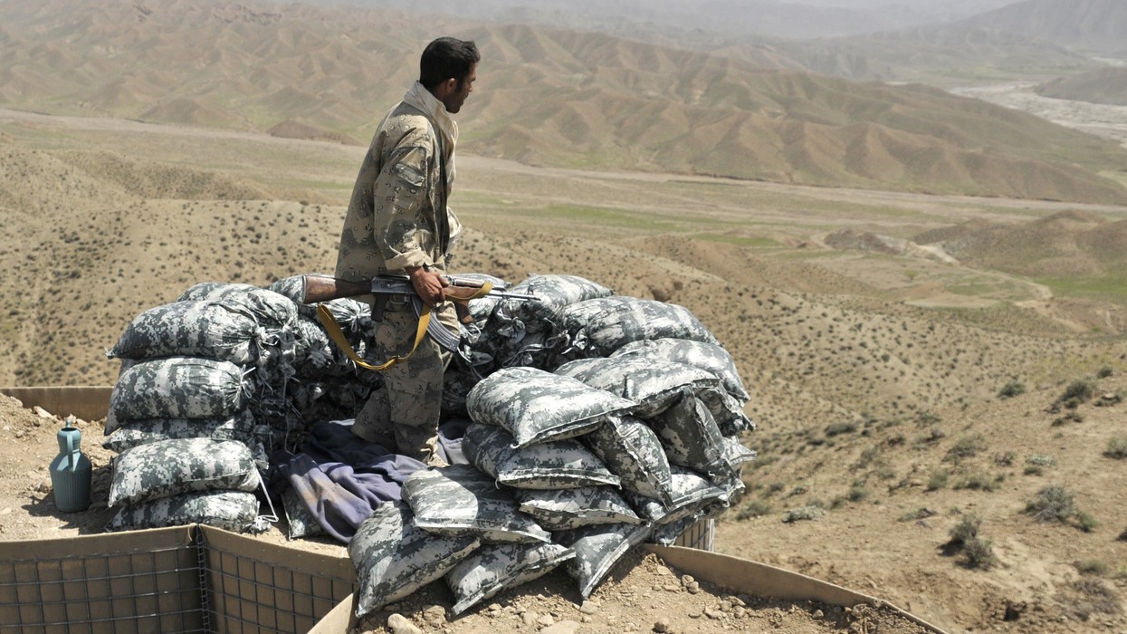 A soldier standing on sandbags overlooking a valley