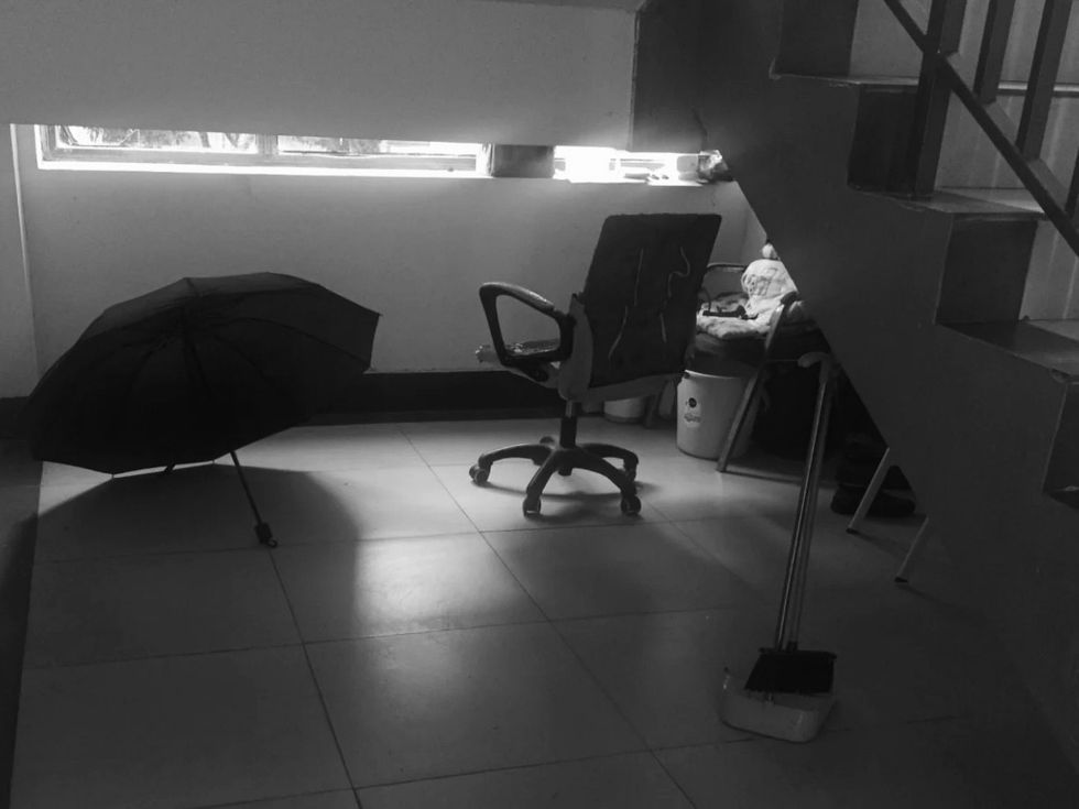 A space with a chair and an umbrella under the stairs