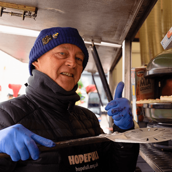 A triptych of pictures - a man looking at pizza ovens, another wearing gloves pulls a pizza paddle out of the oven, a pizza bakes in the oven.