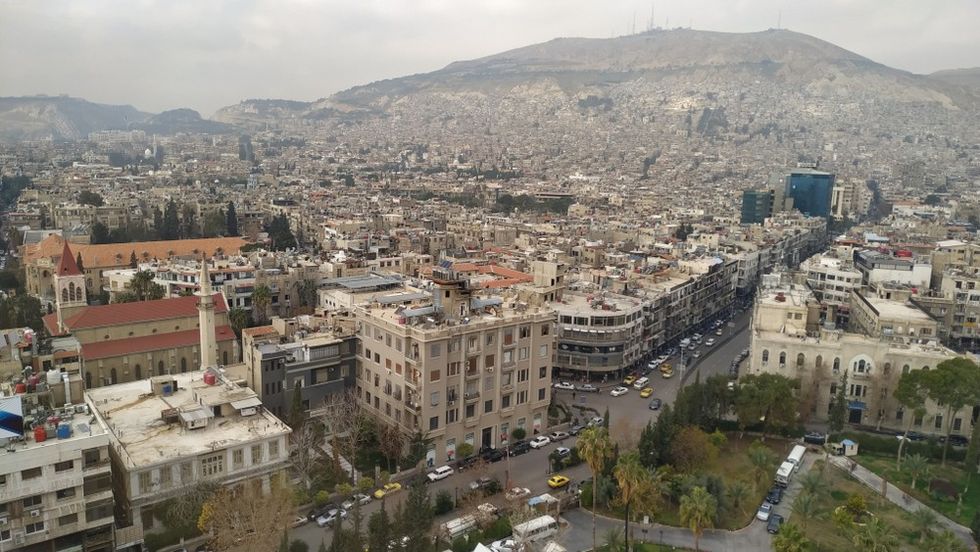 A wide shot of a city at the foot of a hill
