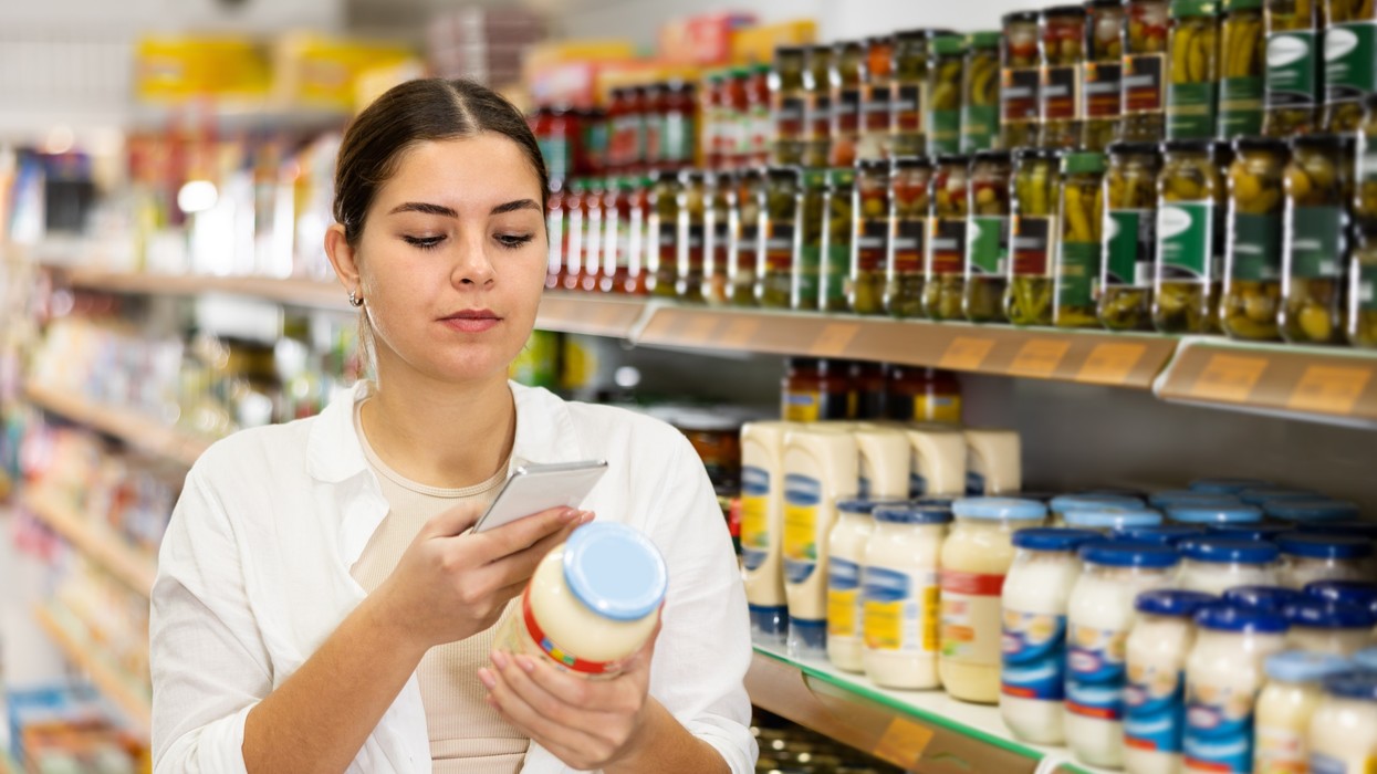A woman checks the labels of a jar of mayonnaise in the supermarket