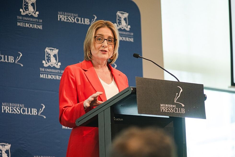 A woman in a red suit speaking at a dias