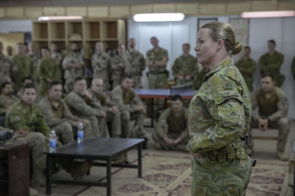 A woman in fatigues faces the armed forces