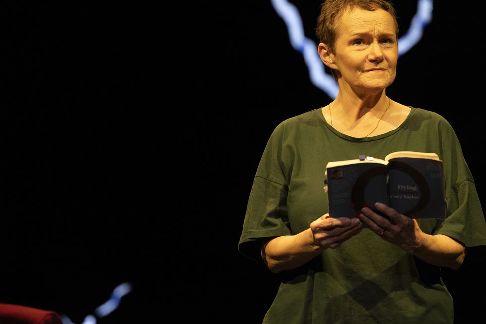 A woman on stage reading from a book