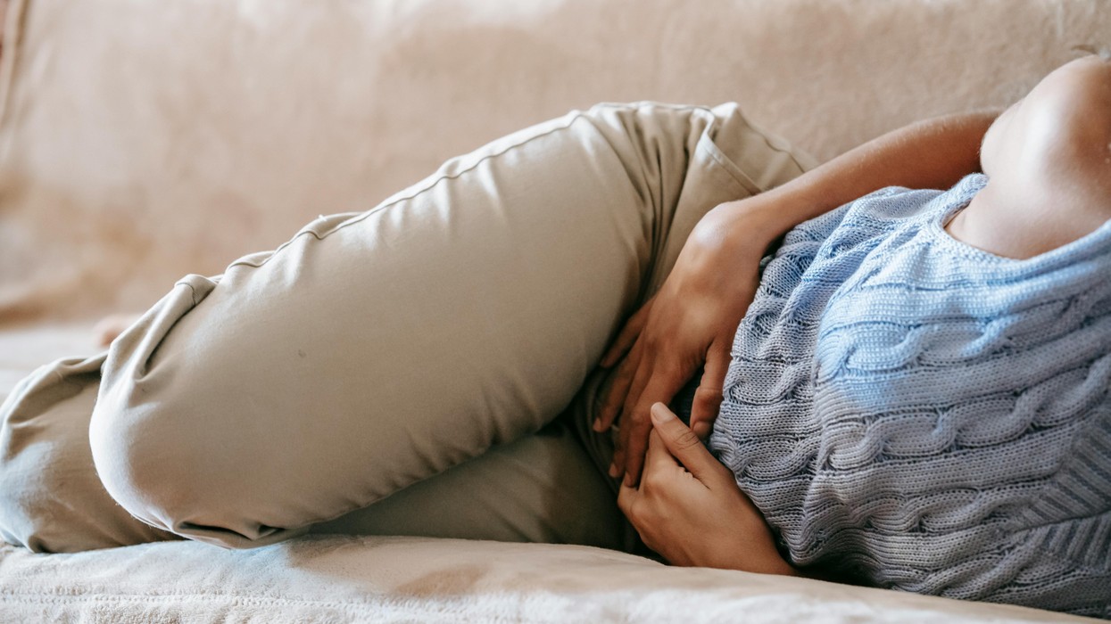 A woman on the couch with hands on lower abdomen