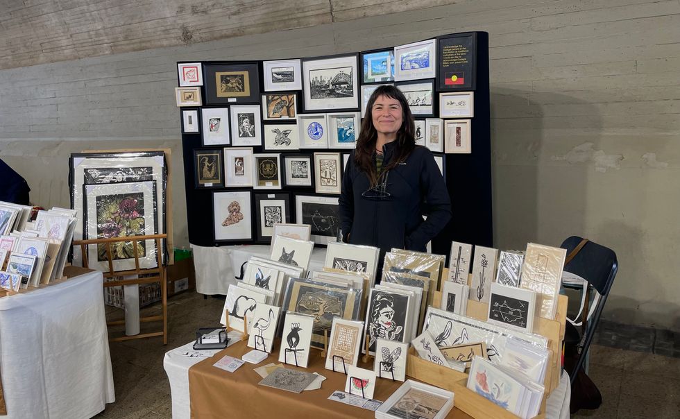 A woman standing behind a table selling art