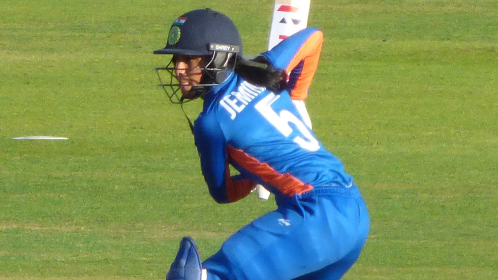 A woman wearing a cricket helmet steps up to bat
