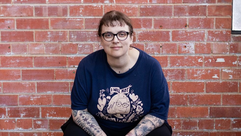 A woman wearing dark rimmed glasses smiles that the camera 