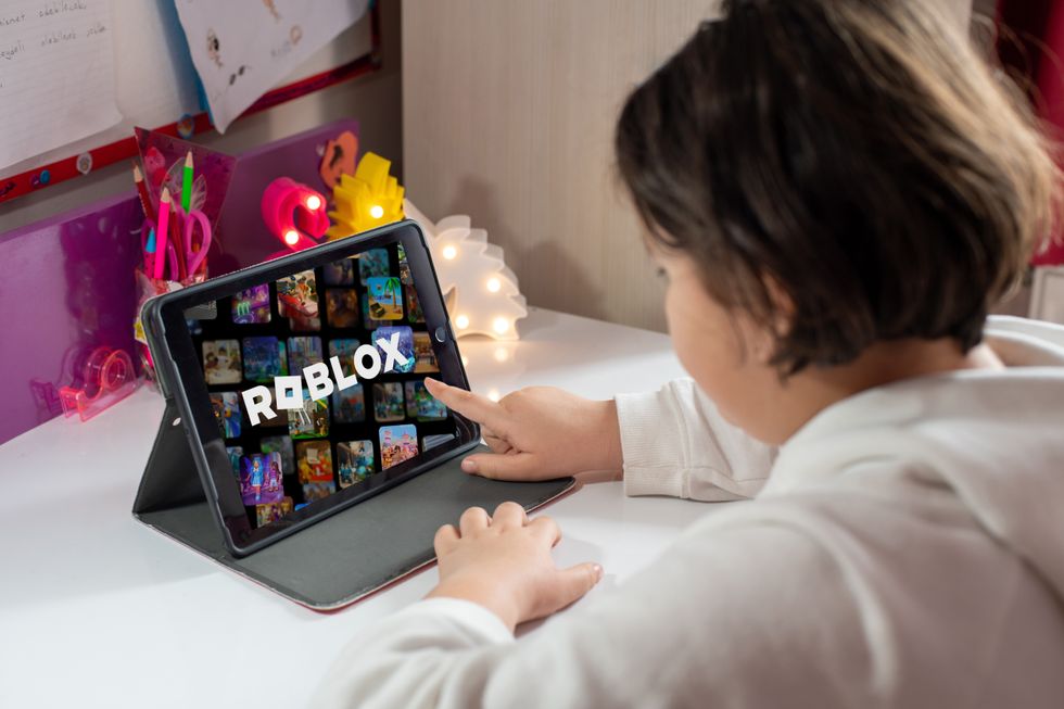 A young person playing with Roblox on an iPad
