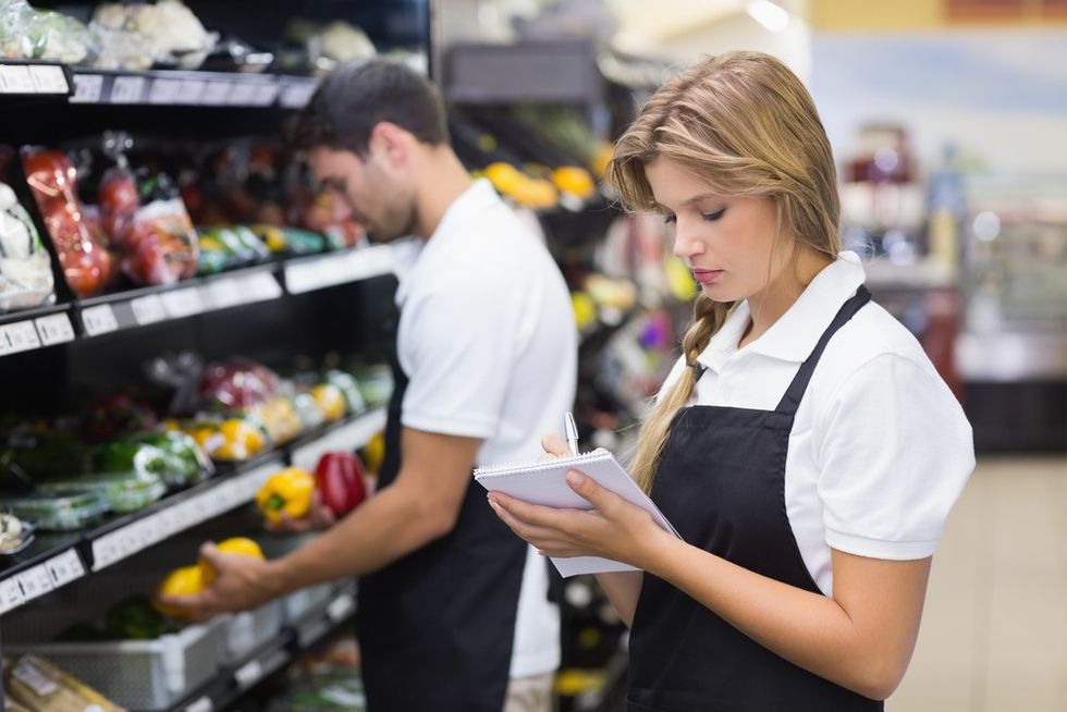 A young supermarket worker looking at a list
