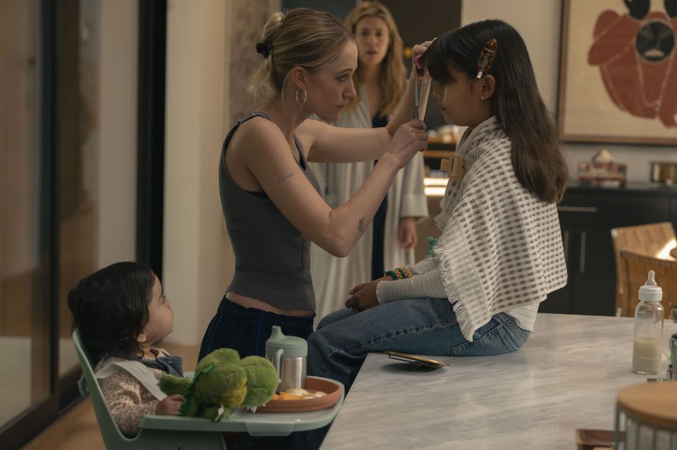 A young woman trims a little girl's fringe.